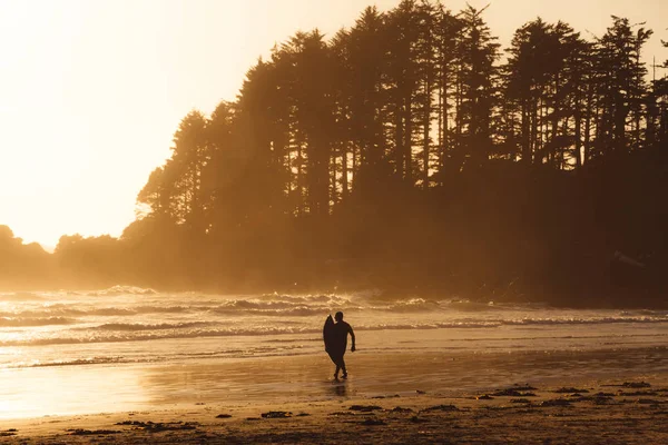 波の上を歩く男、中の背後にある森とビーチ — ストック写真