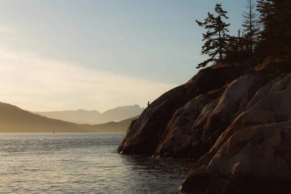 Tramonto sulla costa con scogliere e montagne sullo sfondo — Foto Stock