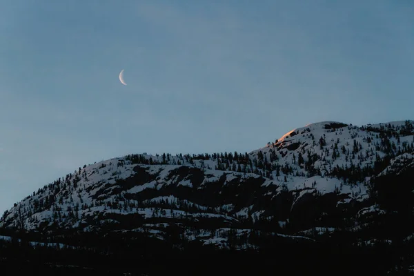 Morgon bergslandskapet i skugga med månen på himlen medan sunris — Stockfoto