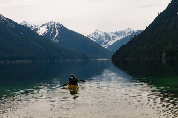 Zataženo krajina s kánoí na jezero a sníh zahrnuty hory — Stock fotografie