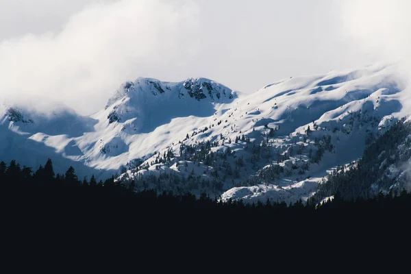 Gefrorene Winterlandschaft mit großen Bergen, die von Wolken bedeckt sind und — Stockfoto