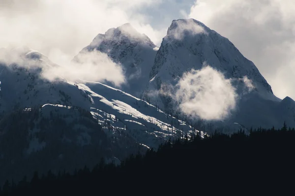 Gefrorene Winterlandschaft mit großen Bergen, die von Wolken bedeckt sind und — Stockfoto