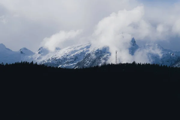 Gefrorene Winterlandschaft mit großen Bergen, die von Wolken bedeckt sind und — Stockfoto