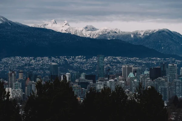 Cidade nublada com montanhas na neve no fundo — Fotografia de Stock