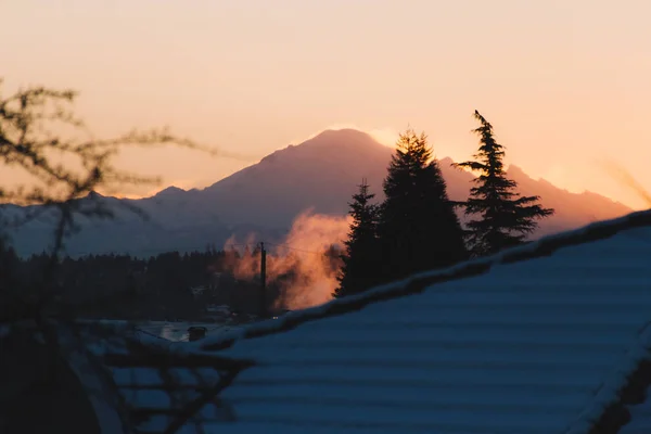 Montagne innevate con edificio di fronte al tramonto o all'alba — Foto Stock