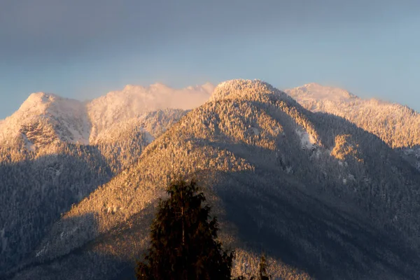Montagnes dans la neige avec lumière orange du lever du soleil ou du susnet — Photo