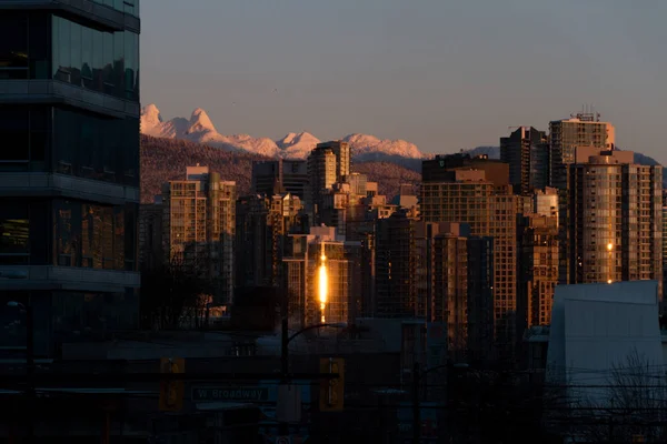 Paisaje urbano de invierno con montañas y amanecer iluminando el edificio — Foto de Stock