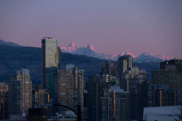 Paisaje urbano de invierno con montañas y amanecer iluminando el edificio — Foto de Stock