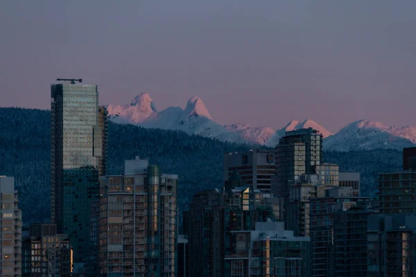 Paisagem urbana de inverno com montanhas e nascer do sol iluminando buildin — Fotografia de Stock