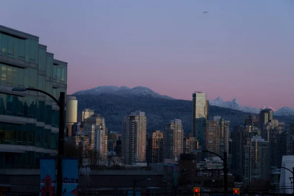 Paisaje urbano de invierno con montañas y amanecer iluminando el edificio — Foto de Stock