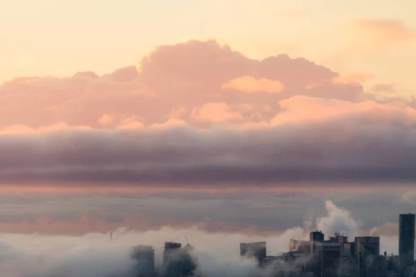 Colorful sunrise in city in clouds and fog — Stock Photo, Image