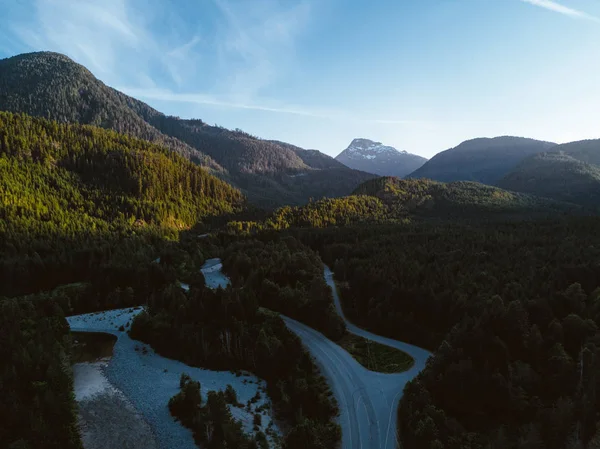 Tiro aéreo de estrada no vale enquanto o pôr do sol atrás da montanha — Fotografia de Stock