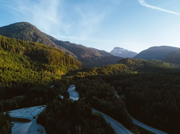 Tiro aéreo de estrada no vale enquanto o pôr do sol atrás da montanha — Fotografia de Stock