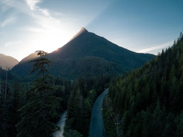 Tiro aéreo de estrada no vale enquanto o pôr do sol atrás da montanha — Fotografia de Stock