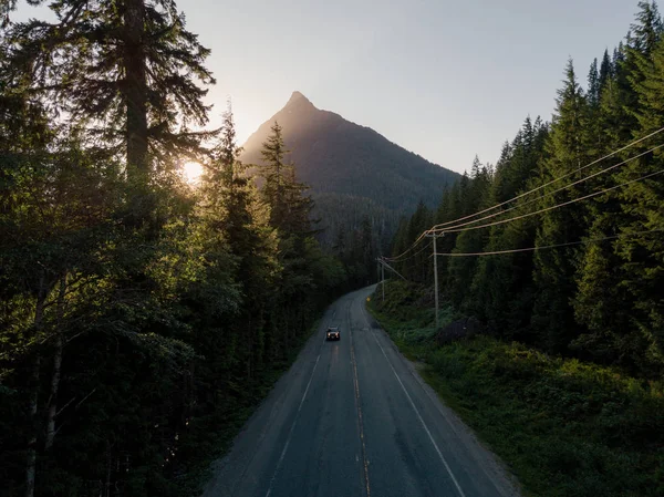Tiro aéreo de estrada no vale enquanto o pôr do sol atrás da montanha — Fotografia de Stock
