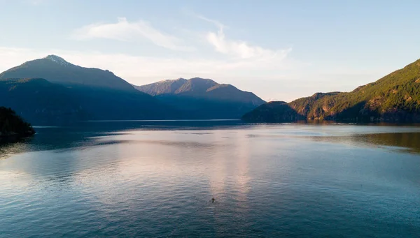 Colpo aereo di kayaker sul lago con le montagne durante il tramonto — Foto Stock