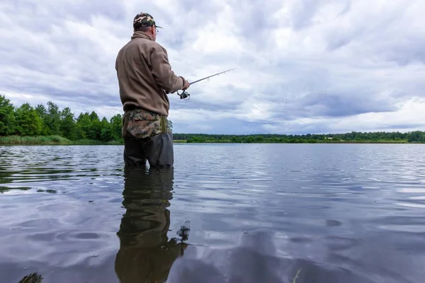 曇りの日に釣り人が湖で魚を捕まえる — ストック写真