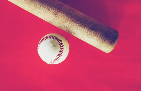 Baseball bat and ball on red background.