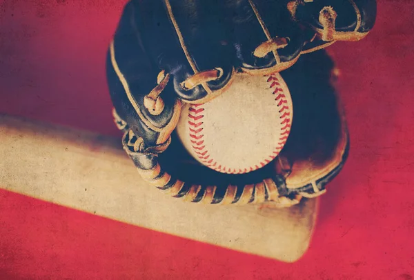 Baseballová rukavice držení míče s dřevěnou pálkou v pozadí. — Stock fotografie