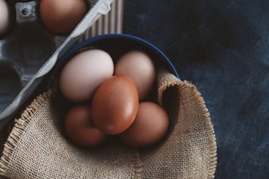 Brown chicken eggs for flat lay close up in bowl with burlap background.
