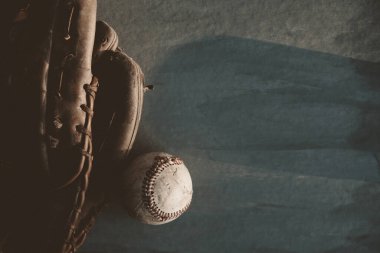 Old used baseball with glove on dark background, copy space for sports concept.