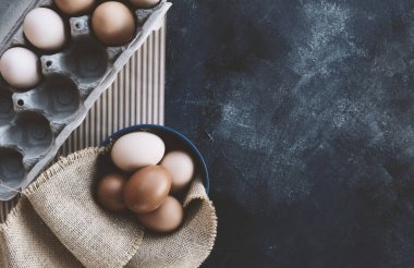 Chicken eggs in carton and bowl on background with copy space.