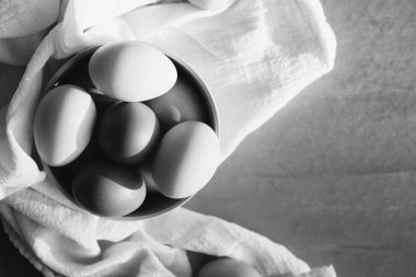 Raw chicken eggs, top view with bowl in black and white.
