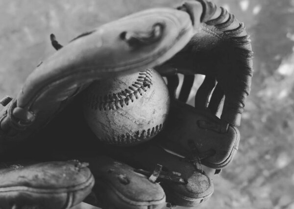Texture of old used ball in baseball glove, black and white sport equipment.