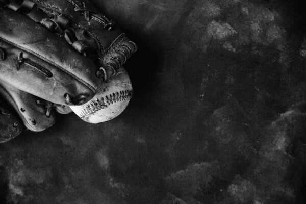Top view of baseball with ball glove on black and white texture background.
