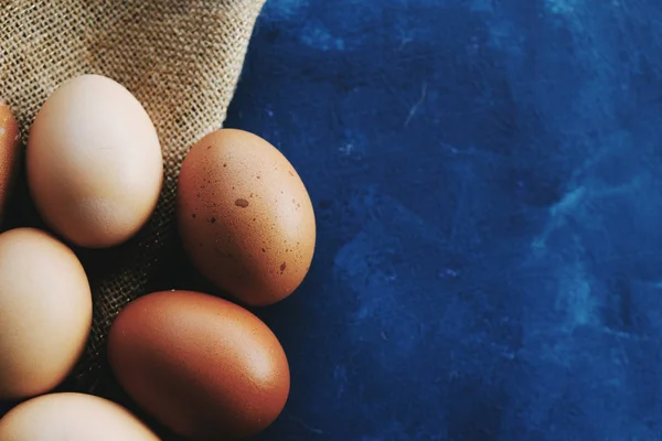 Brown cage free organic chicken eggs contrast on blue background.