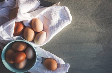 Kumaş üzerinde tavuk yumurtası olan kasenin üst görüntüsü.