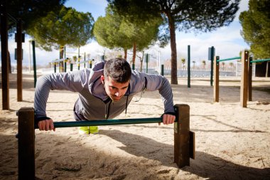 Genç sporcu adam bir parkta egzersiz yapıyor