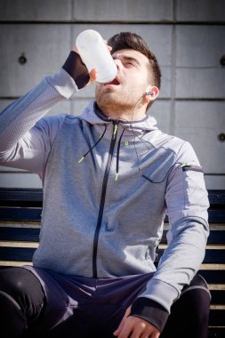 Bir parkta çalıştırdıktan sonra genç sporcu adam içme suyu