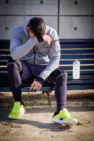 Young athlete man resting after running in a park