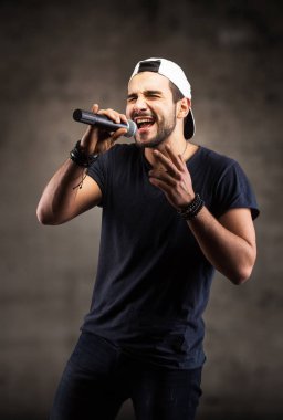 Genç adam mikrofona şarkı söylüyor.