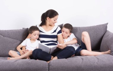 Anne kanepenin oğulları ile ilginç bir kitap okur. 