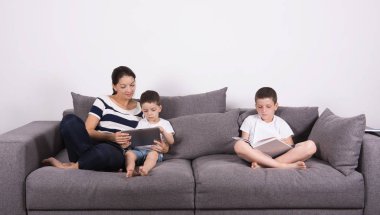 Anne kanepenin oğulları ile ilginç bir kitap okur. 