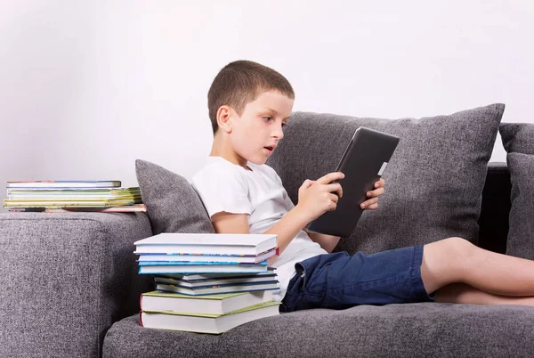 Мальчик с планшетным компьютером на диване . — стоковое фото