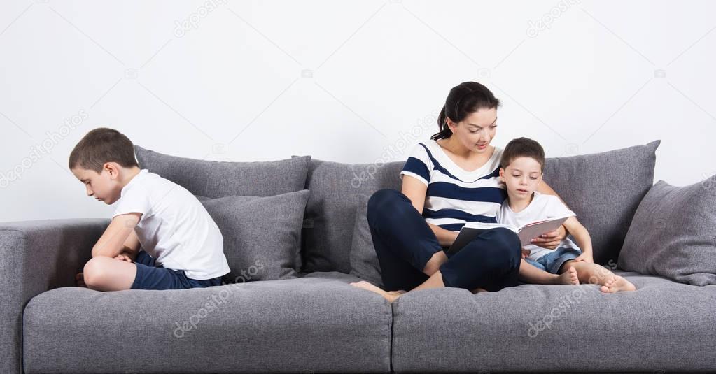 Mother reads an interesting book with her son. Jealousy concept.