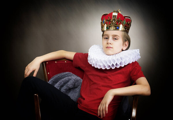 Crowned boy sitting in an armchair