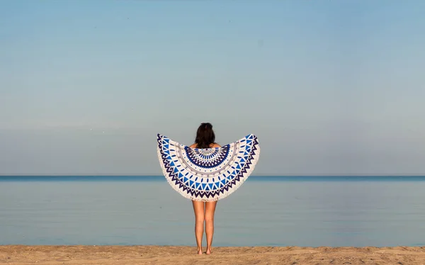Hübsche Frau mit einem Mandala runden Strandteppich im Ozean co — Stockfoto