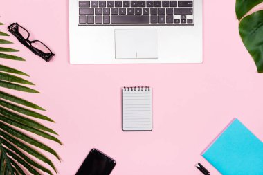 Laptop bilgisayarı ve günlük planlayıcısı olan, tropikal dekorasyonlu bir ofis. Sosyal medya için yapılacaklar listesi konsepti düzlüğü