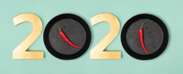 2020 eve top view new year number and pans with hot chillie pepperes as zero numbers. Flat lay style on neon mint background, banner template.