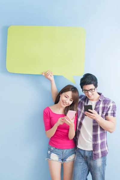 Pareja joven con teléfonos y burbuja del habla — Foto de Stock