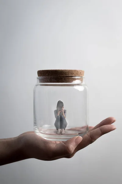 woman sitting  imprisoned in jar