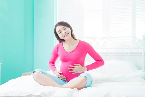 Kobieta w ciąży, uśmiechając się na łóżku — Zdjęcie stockowe