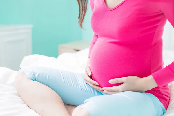 Gravid kvinna sitter på sängen — Stockfoto