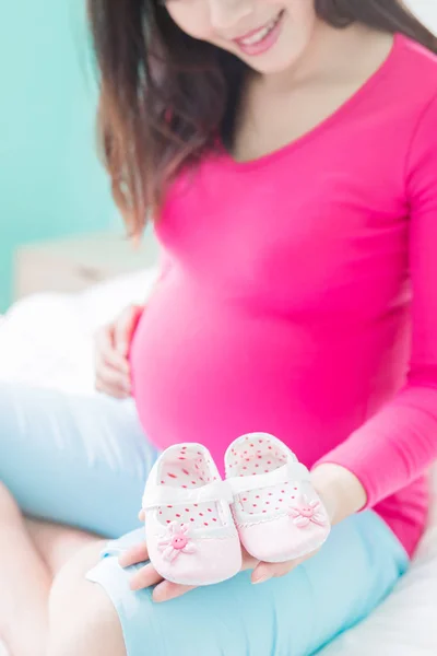 아기 신발을 신고 있는 임산부 — 스톡 사진