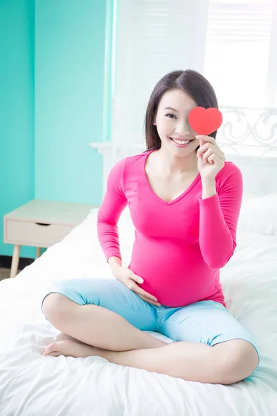 Woman with  heart on the bed — Stock Photo, Image