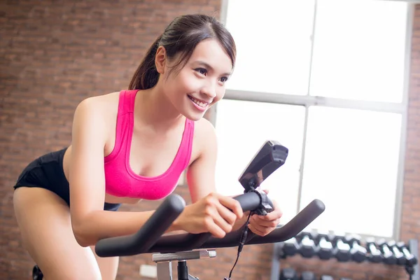 Mulher usando bicicleta de exercício — Fotografia de Stock